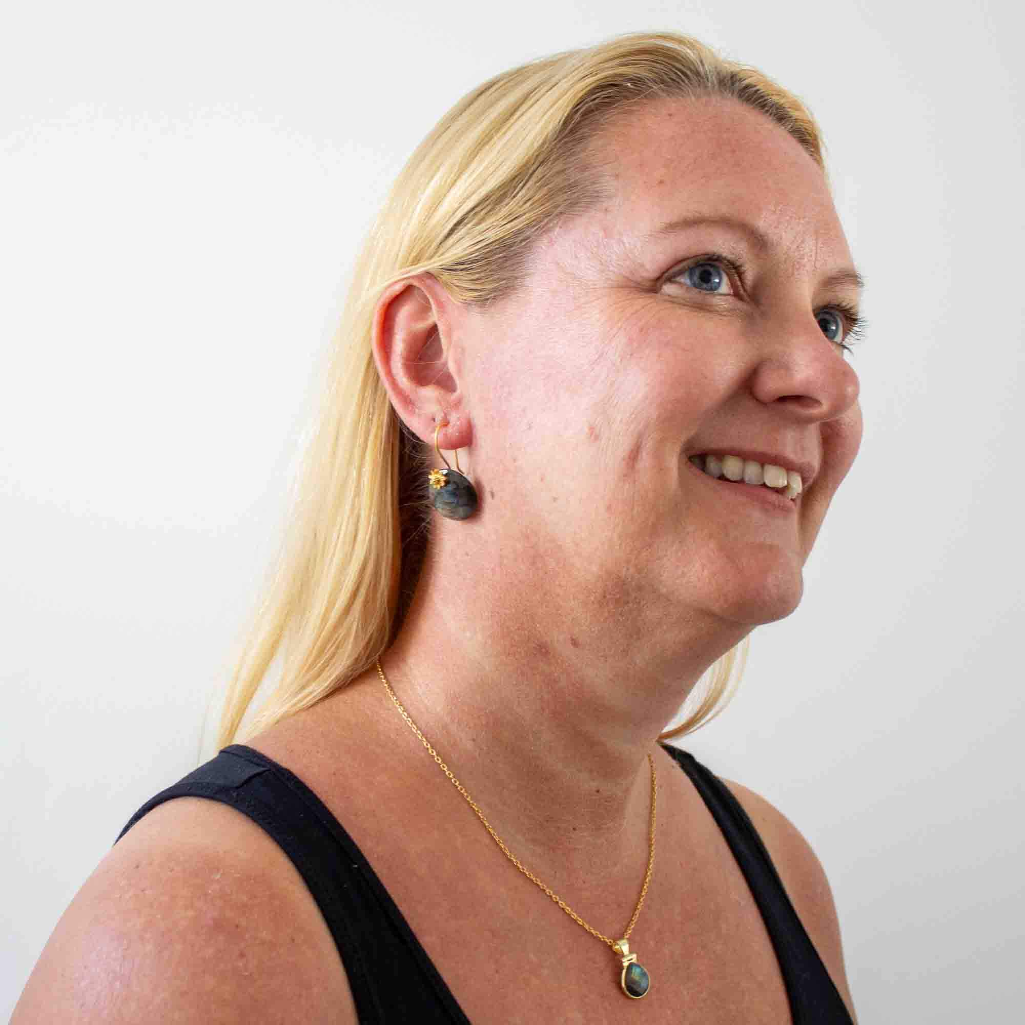 Model wearing Round labradorite gemstone earrings with 18k gold vermeil flower detail and hook fittings - Beyond Biasa