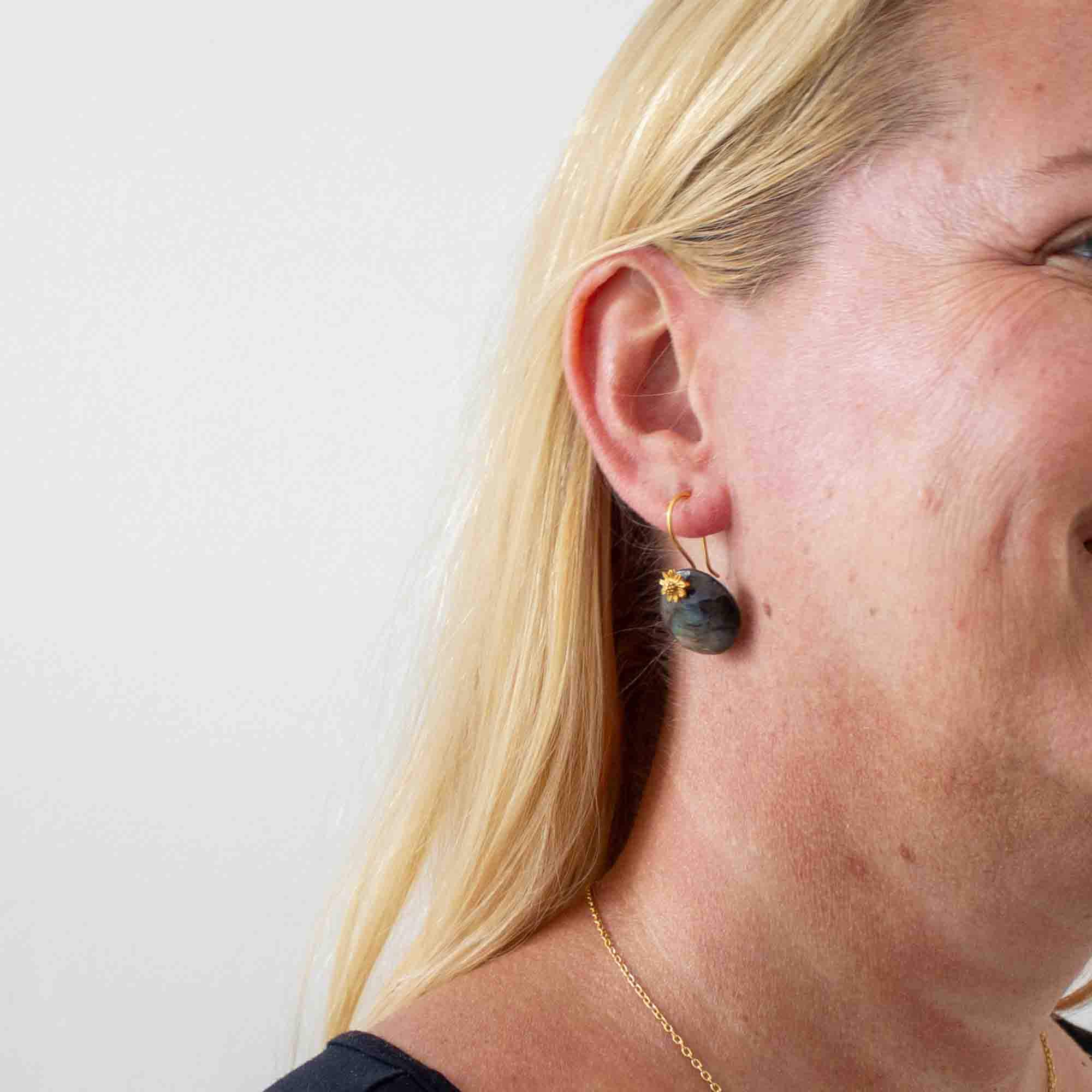 Model wearing Round labradorite gemstone earrings with 18k gold vermeil flower detail and hook fittings - Beyond Biasa