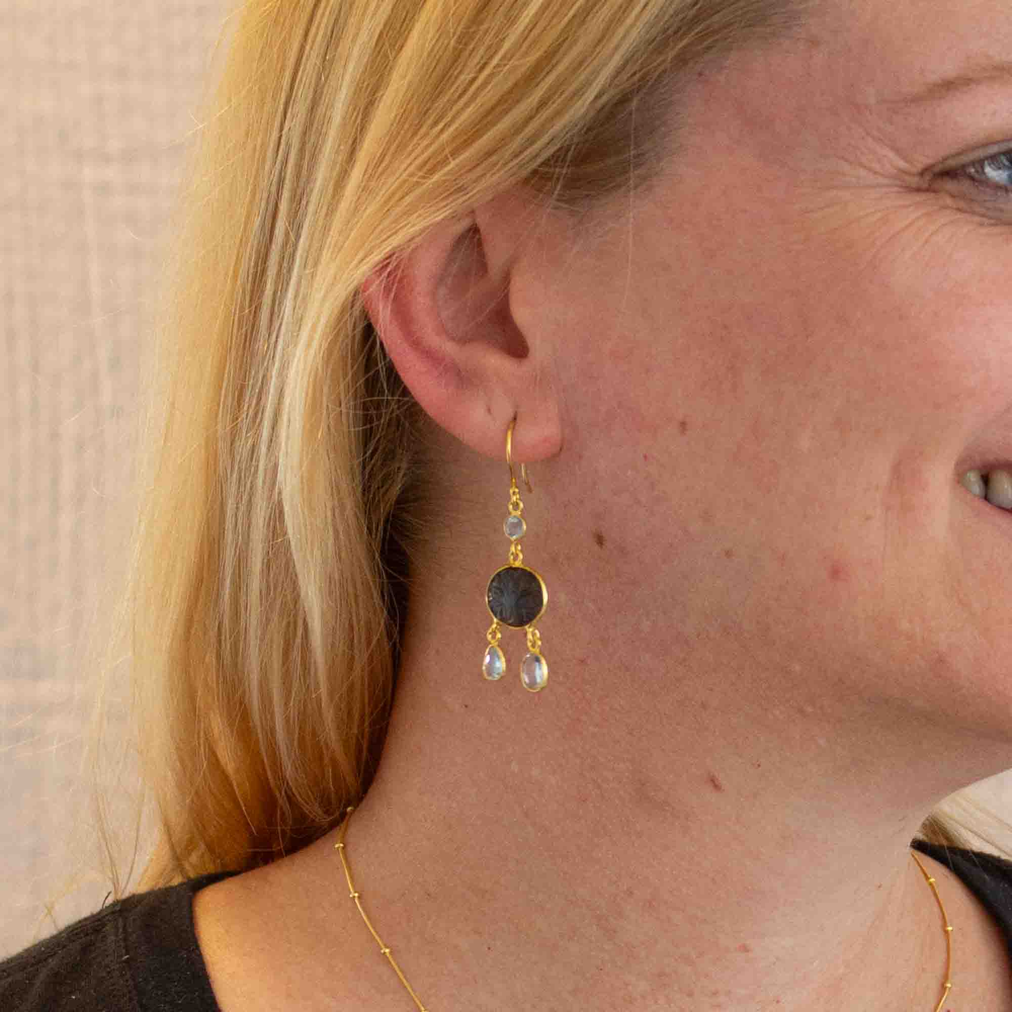 Model with blond hair wearing carved labradorite and blue topaz gemstone earrings with 18k gold vermeil setting and hook fitting - Beyond Biasa