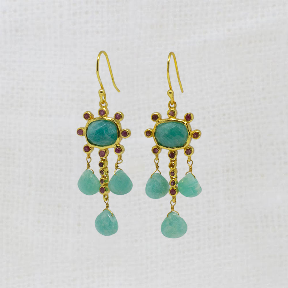 Gold earrings with blue-green amazonite and red ruby gemstones and red accents on a white background