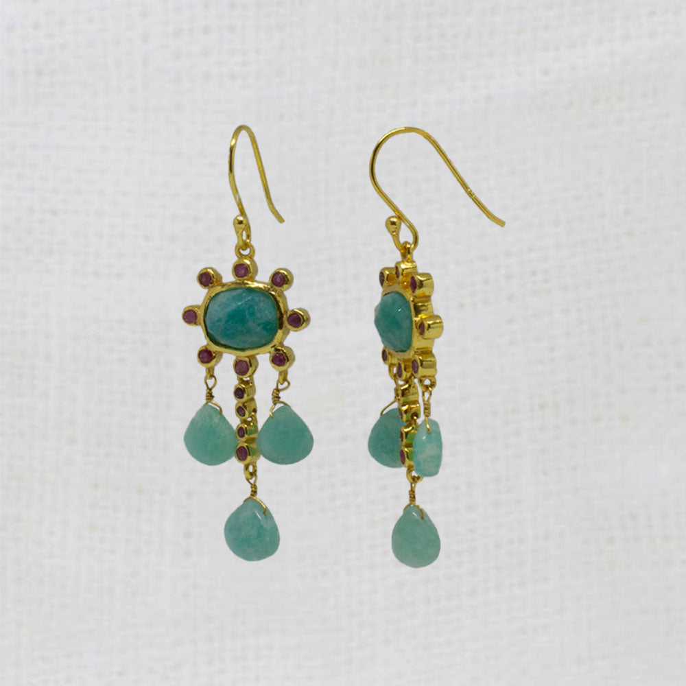 Gold earrings with blue-green amazonite and red ruby gemstones and red accents on a white background