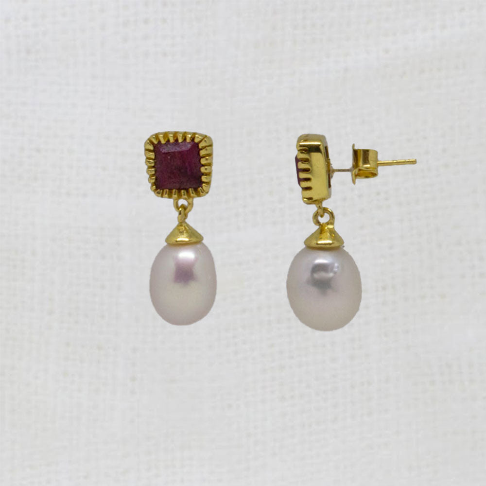 Pair of pearl earrings with gold and red accents on a white background