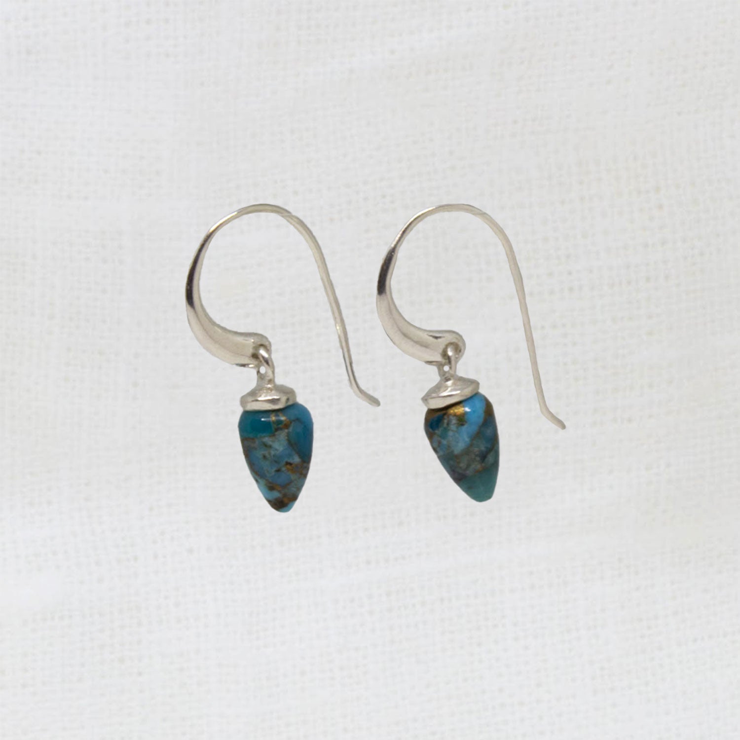 Pair of silver earrings with blue stone drops on a white background