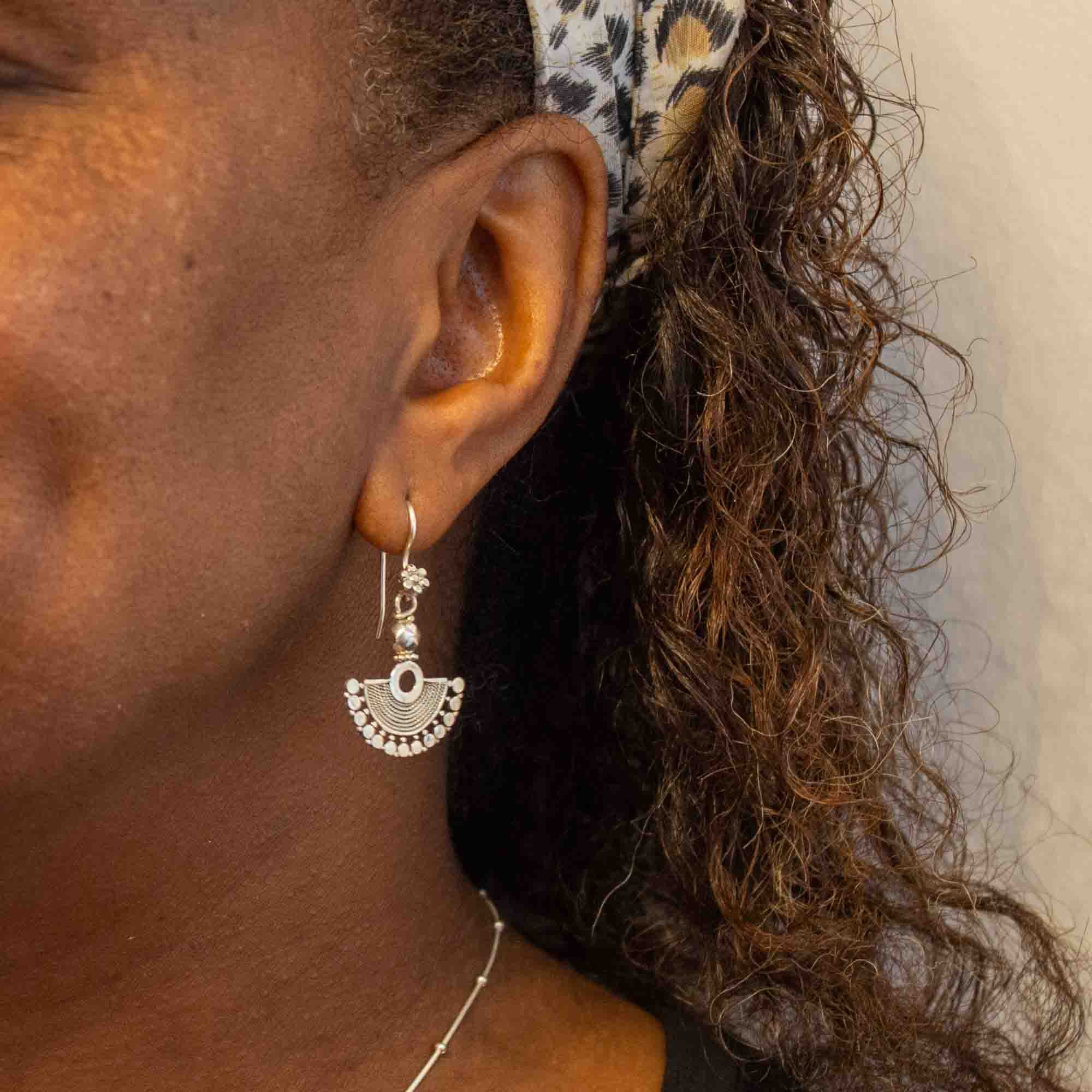 Model wearing Small sterling silver fan shaped earrings, handmade with a detailed wirework finish and hook fittings | Beyond Biasa