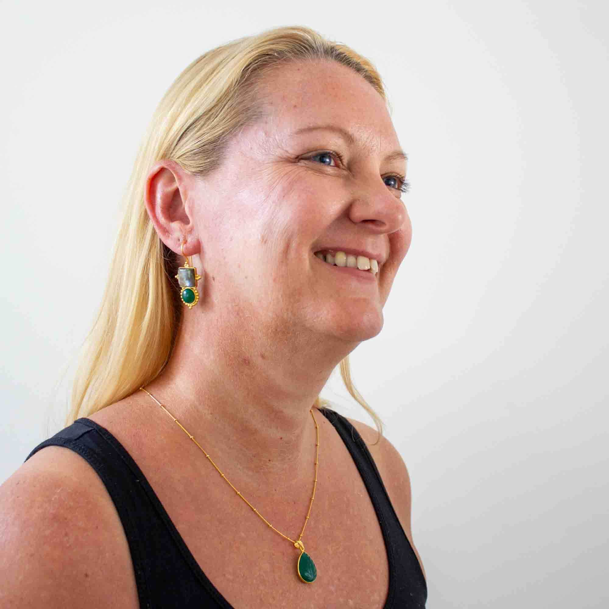 Model wearing Large gemstone drop earrings with a square labradorite and round green onyx in a detailed gold vermeil setting with a hook fitting and carved green onyx teardrop pendant necklace - Beyond Biasa