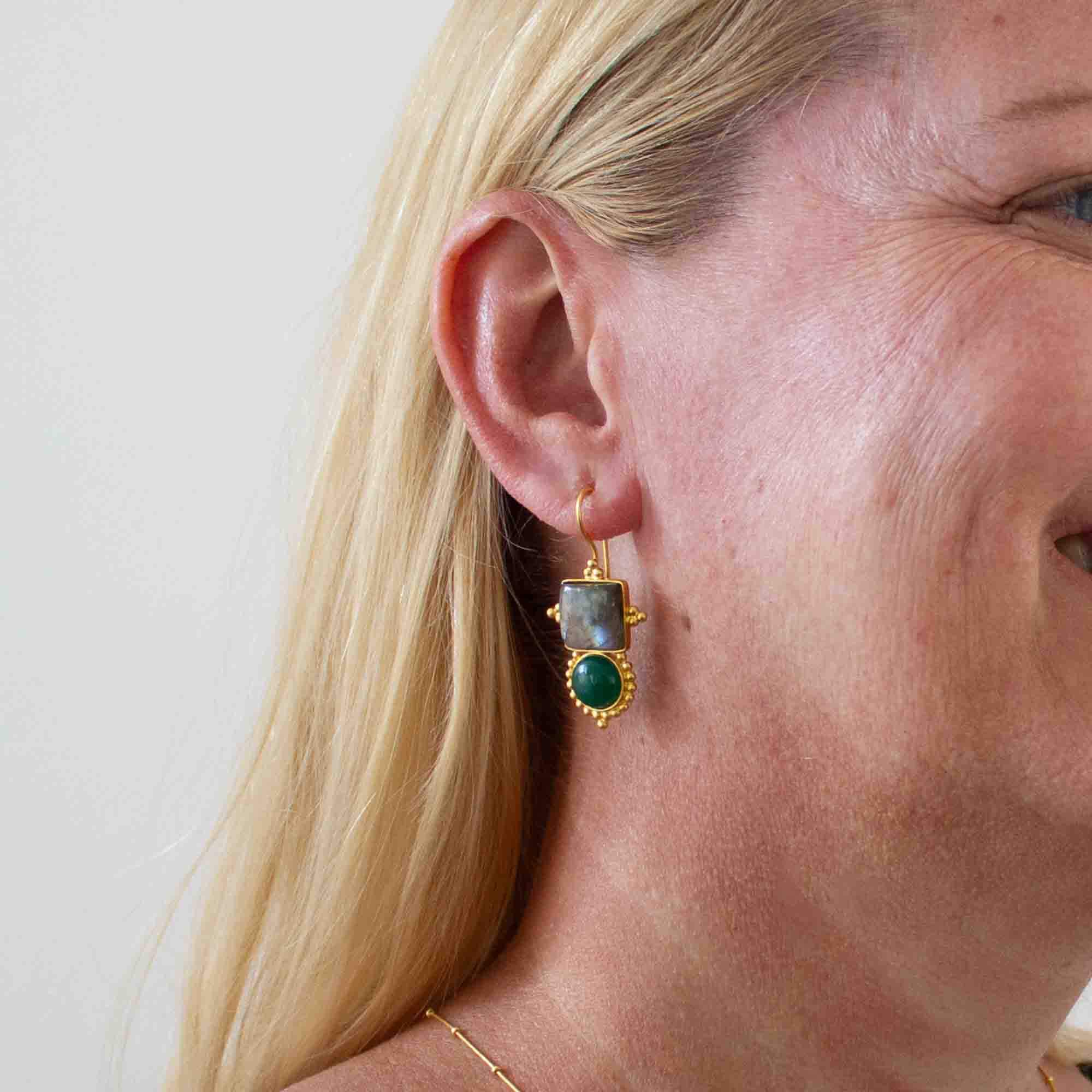 Model wearing Large gemstone drop earrings with a square labradorite and round green onyx in a detailed gold vermeil setting with a hook fitting - Beyond Biasa