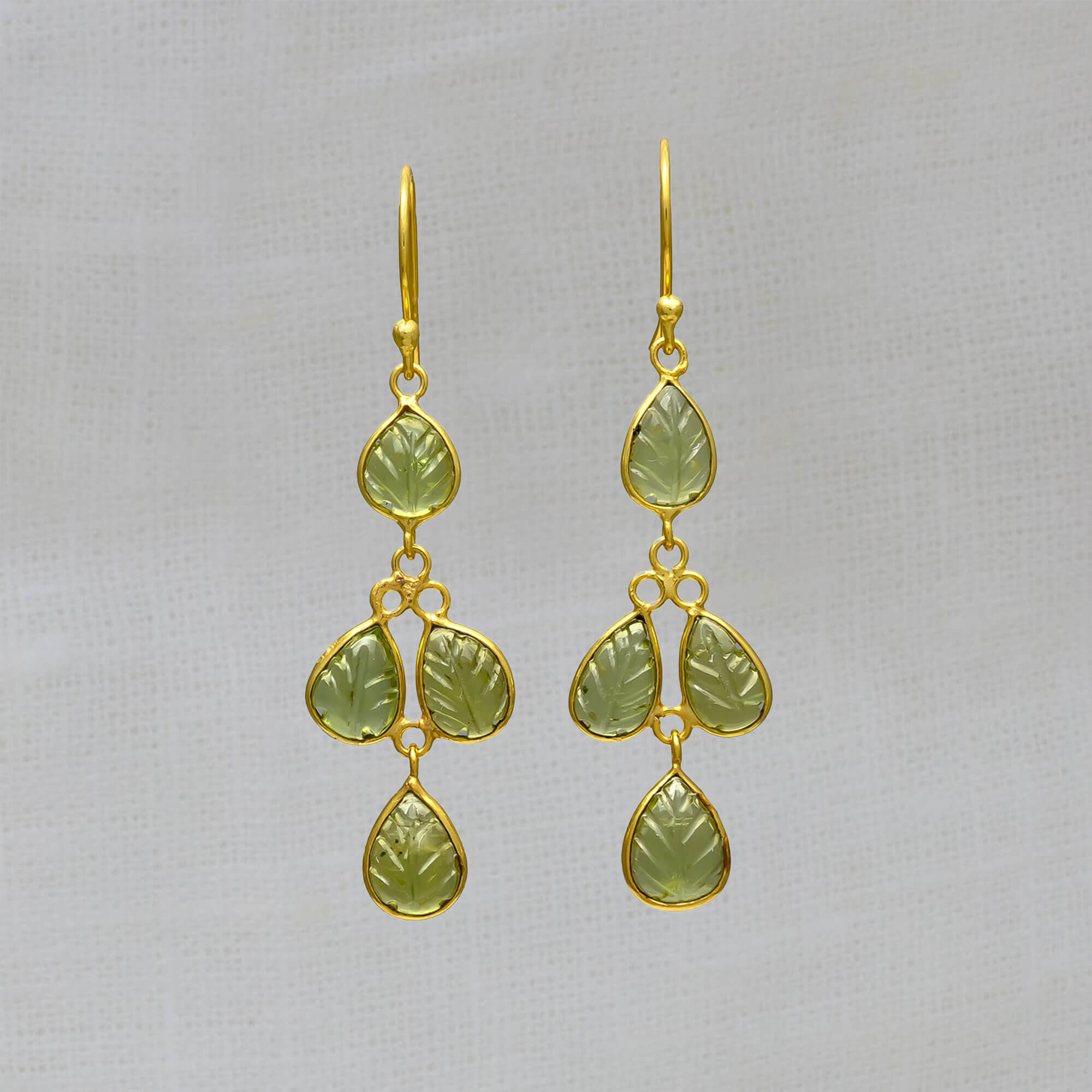 Drop earrings featuring 4 small leaf shaped carved peridot gemstones in a simple 18k gold vermeil setting, with a hook fitting