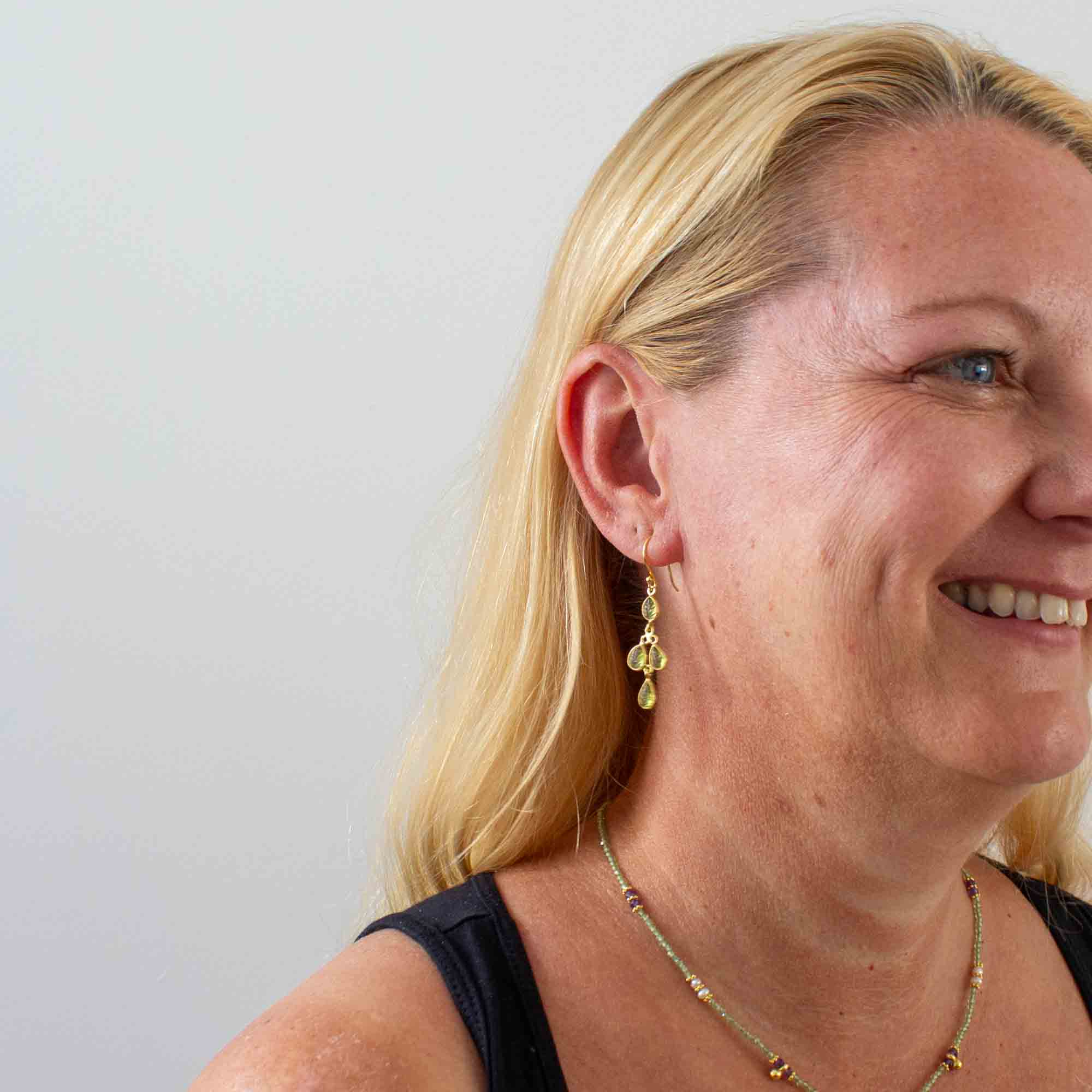 Drop earrings featuring 4 small leaf shaped carved peridot gemstones in a simple 18k gold vermeil setting, with a hook fitting