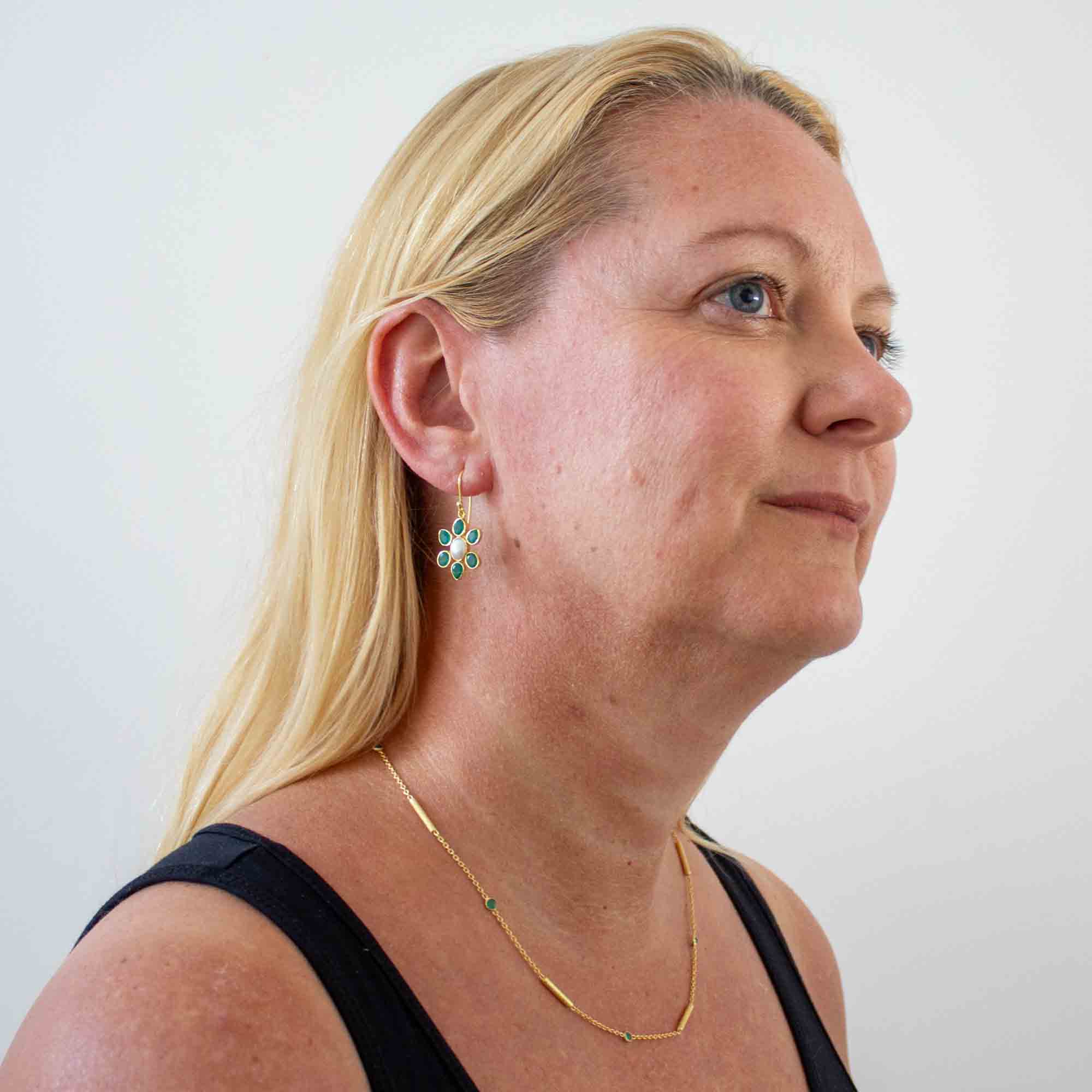 Model wearing 18k gold vermeil flower shaped drop earrings feature a natural freshwater pearl surrounded by 6 green onyx and with a simple hoop fitting | Beyond Biasa