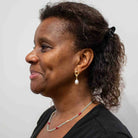 Woman with gemstone beaded necklace and pearl earrings on a plain background