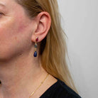 Model wearing  gold earrings with ruby, labradorite and lapis gemstones