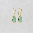 A pair of gold drop earrings with teardrop-shaped aqua chalcedony gemstones. 