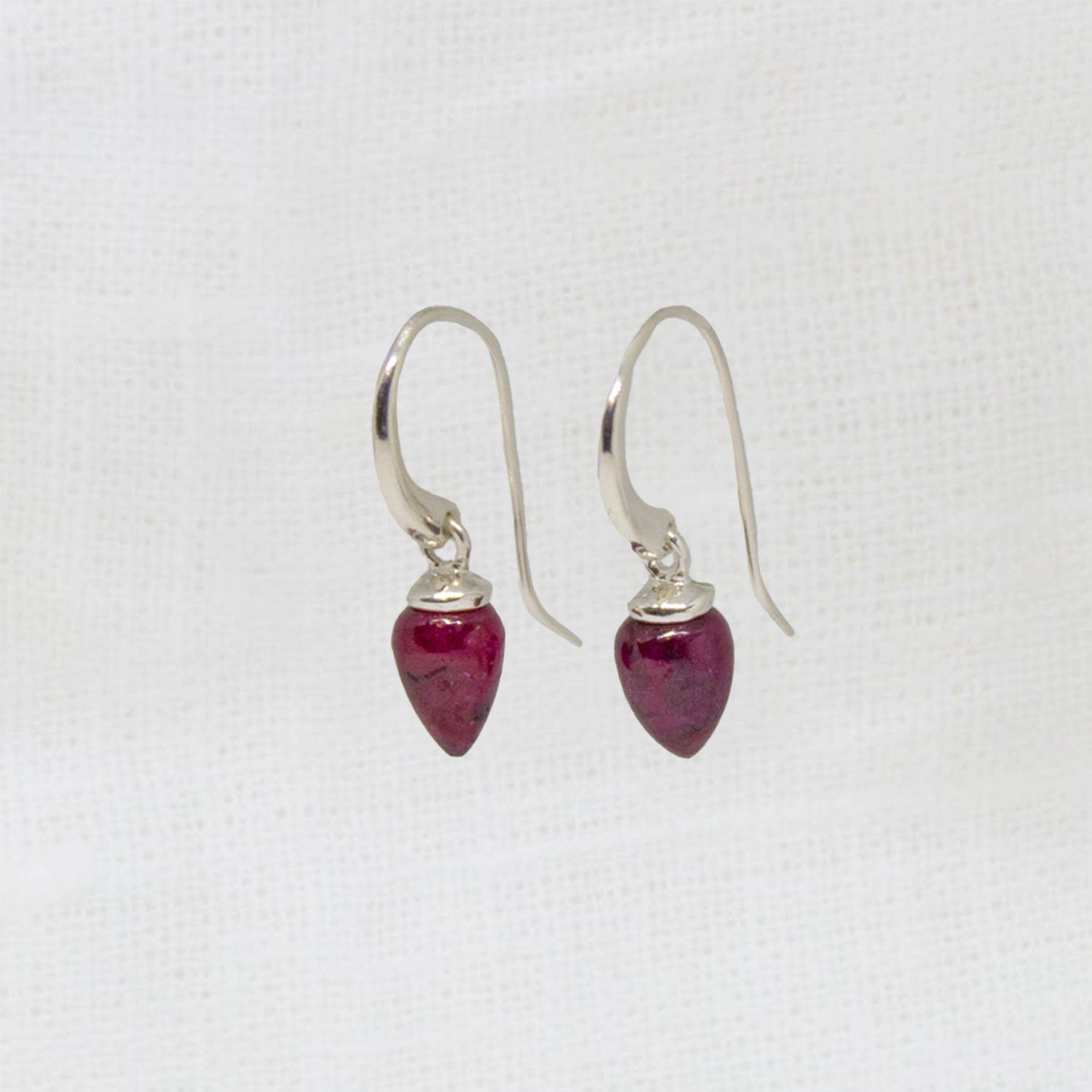 Silver earrings with red gemstones on a white background