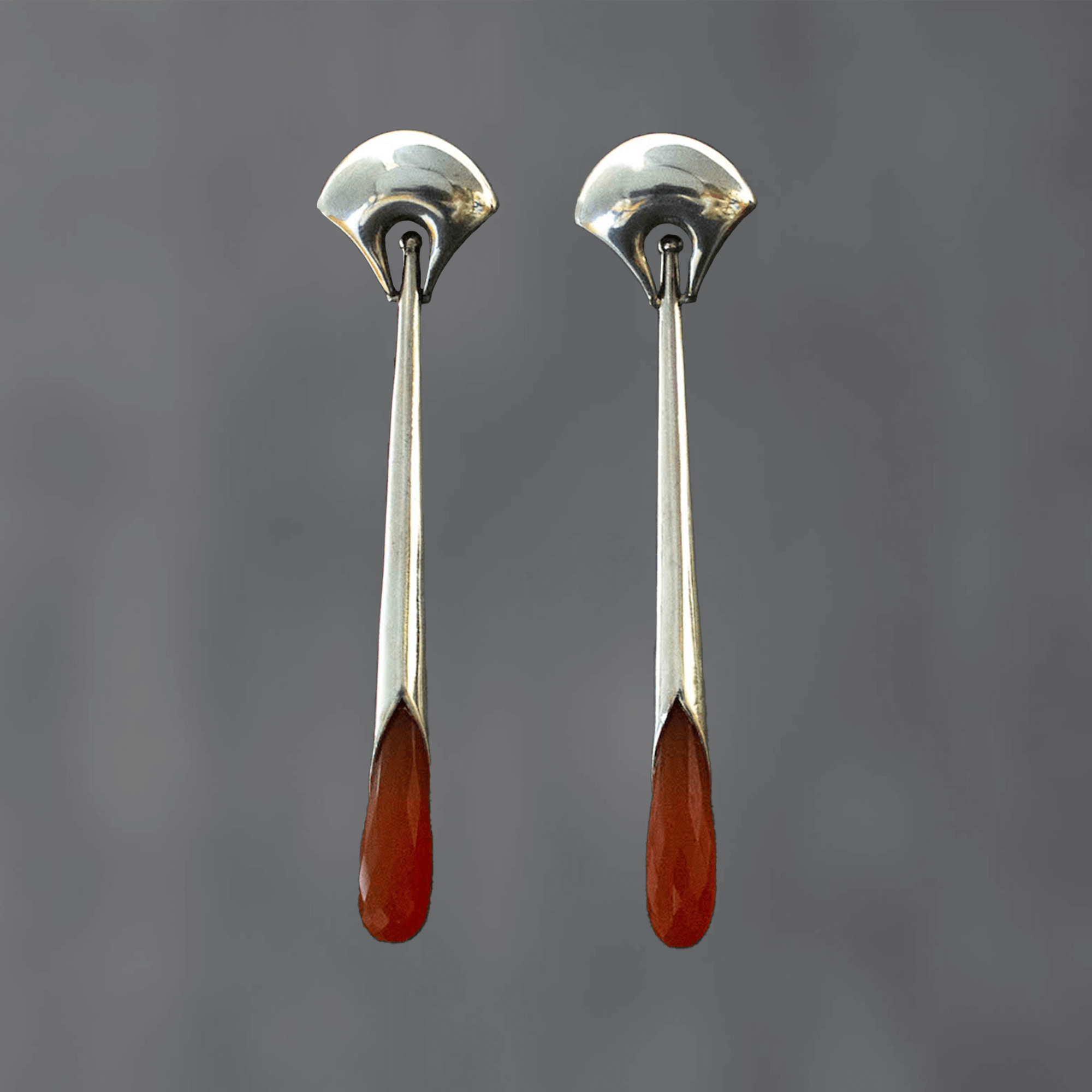 Long statement earrings in sterling silver with a curved stud and long drop with faceted carnelian gemstone