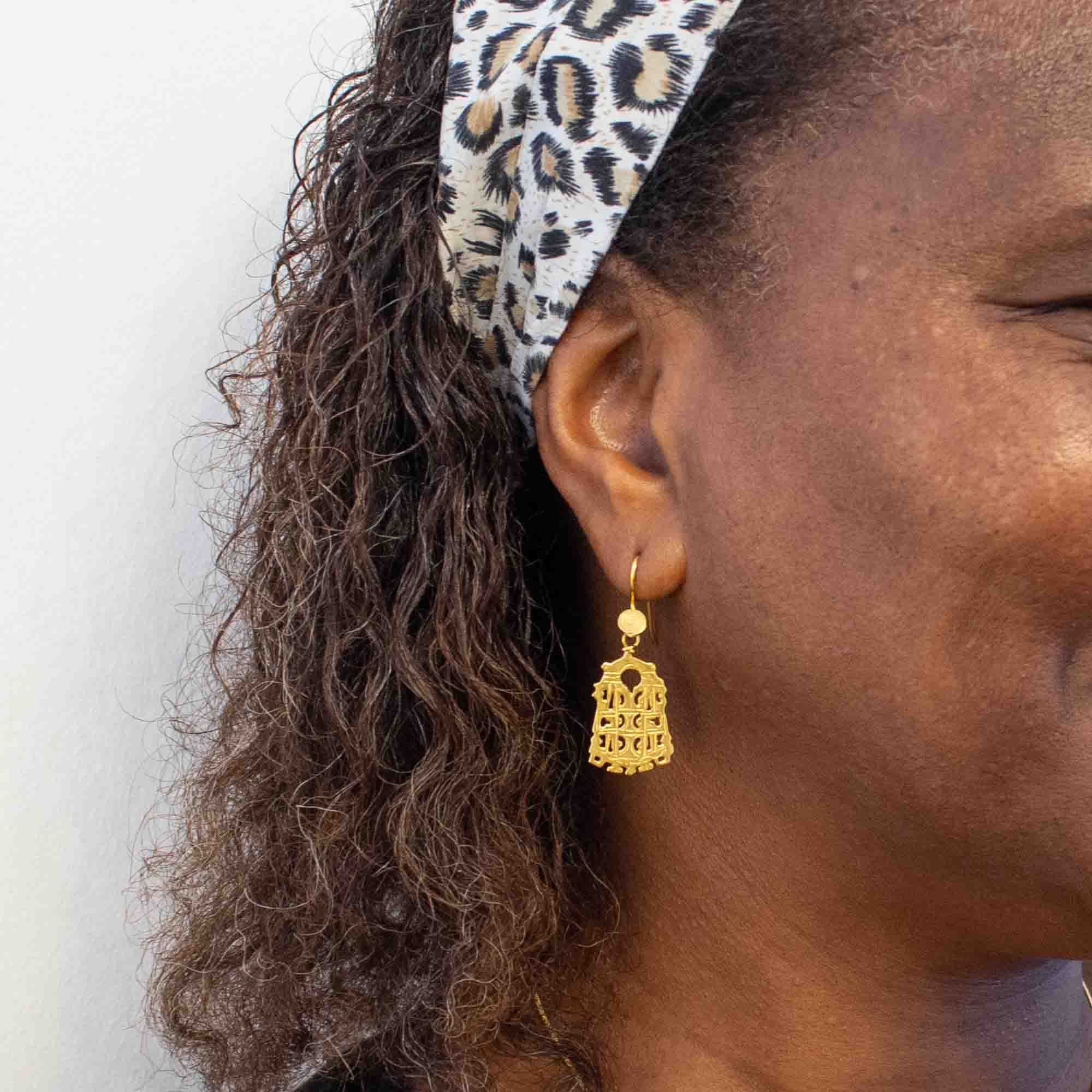 Close-up of a person wearing gold earrings with a white background