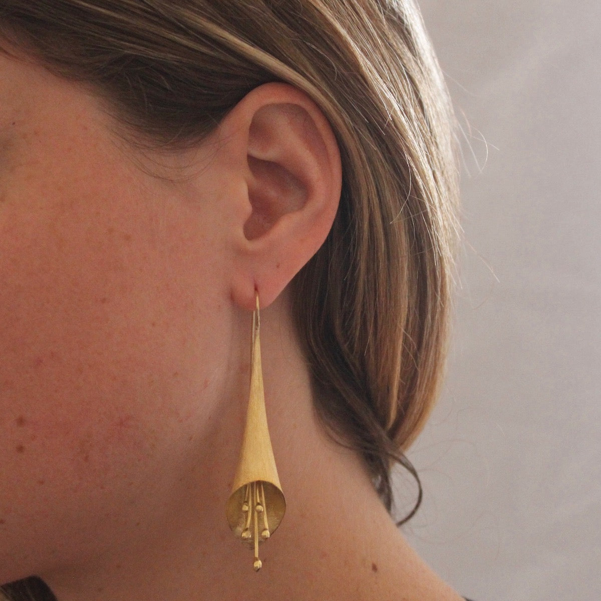 Model wearings Brushed Gold Flower Flute Earrings